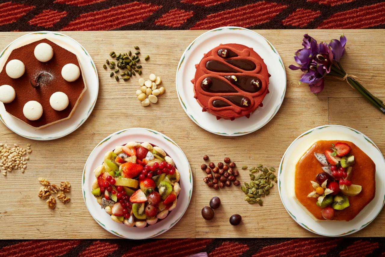 Evergreen Laurel Hotel - Taichung Exterior foto The photo displays a variety of desserts arranged on small plates. There are three main cakes or tarts:

1. **Top Left Plate**: A round chocolate cake with a smooth surface and white decorations on top.
2. **Top Middle Plate**: Another cake, possibly