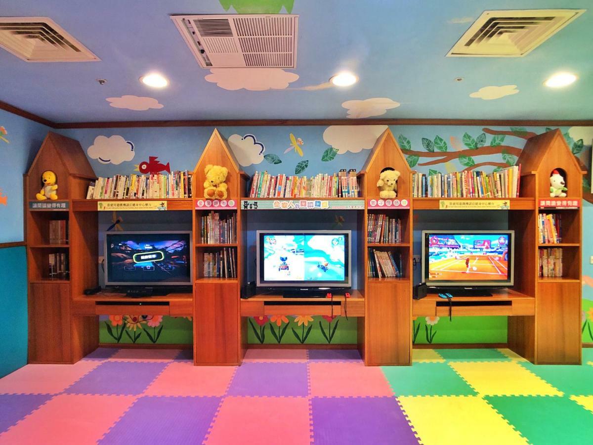 Evergreen Laurel Hotel - Taichung Exterior foto The photo shows a colorful and playful room designed for children. In the center, there are three wooden gaming stations, each equipped with a television screen and surrounded by shelves filled with books. The walls are decorated with cheerful images
